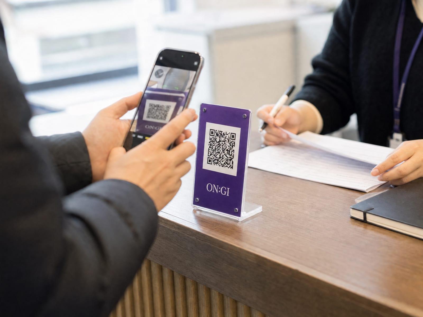 사무실 데스크의 QR 스탠드를 휴대폰으로 스캔하는 모습